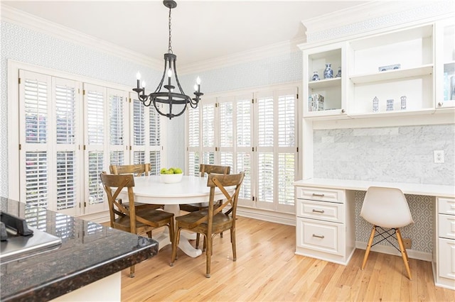 dining space with light wood-style flooring, built in study area, wallpapered walls, an inviting chandelier, and crown molding