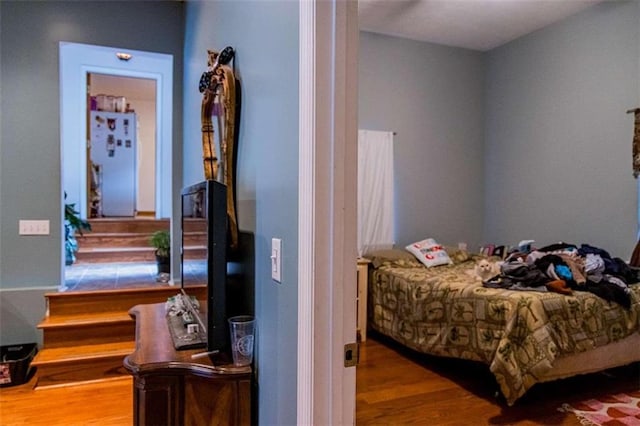 bedroom with wood-type flooring and white fridge