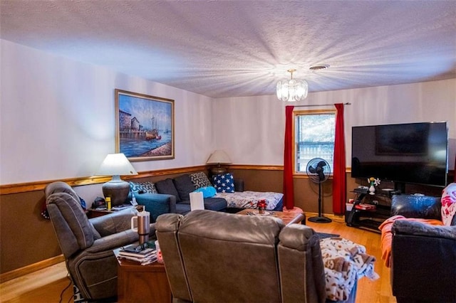 living room featuring hardwood / wood-style flooring, a textured ceiling, and a chandelier