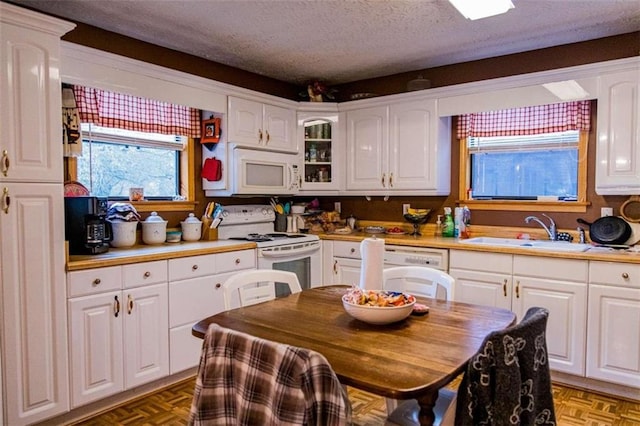 kitchen featuring white cabinetry, sink, parquet floors, a textured ceiling, and white appliances