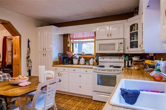 kitchen with white cabinets, a textured ceiling, white appliances, and sink