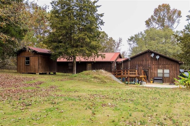 back of property featuring a lawn and an outbuilding