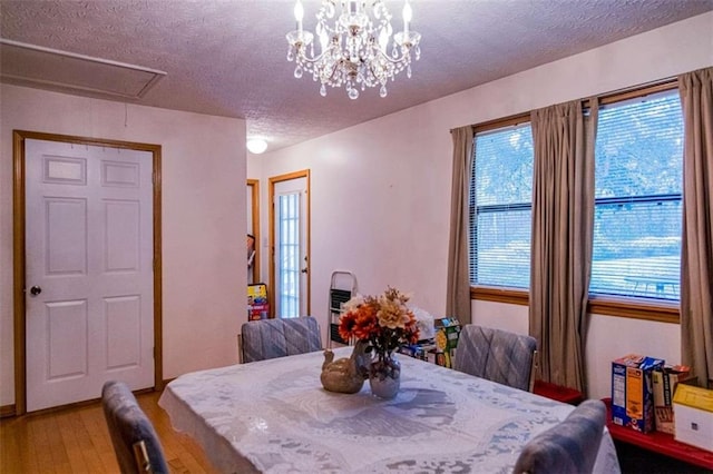 dining room with hardwood / wood-style floors, a healthy amount of sunlight, a textured ceiling, and a notable chandelier