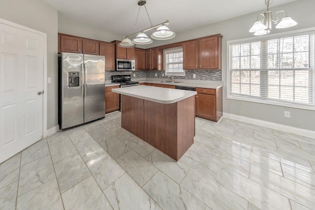 kitchen with marble finish floor, light countertops, decorative backsplash, appliances with stainless steel finishes, and a sink