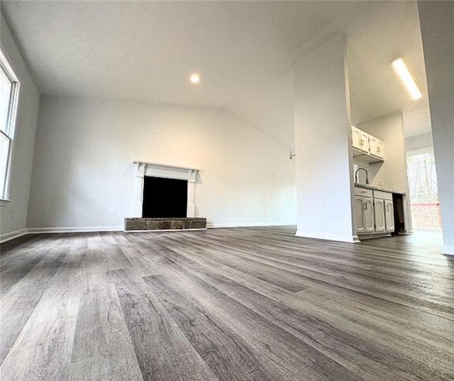 unfurnished living room with lofted ceiling, dark hardwood / wood-style flooring, and a tiled fireplace