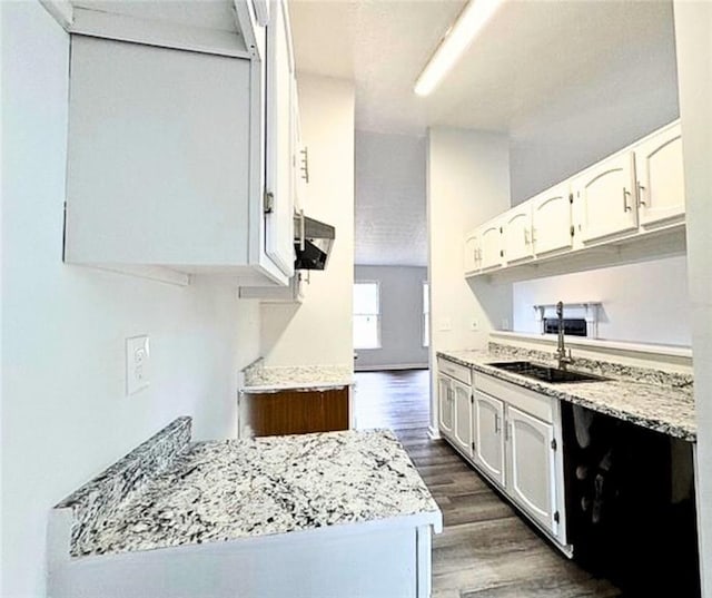 kitchen with dark hardwood / wood-style flooring, sink, light stone counters, and white cabinets