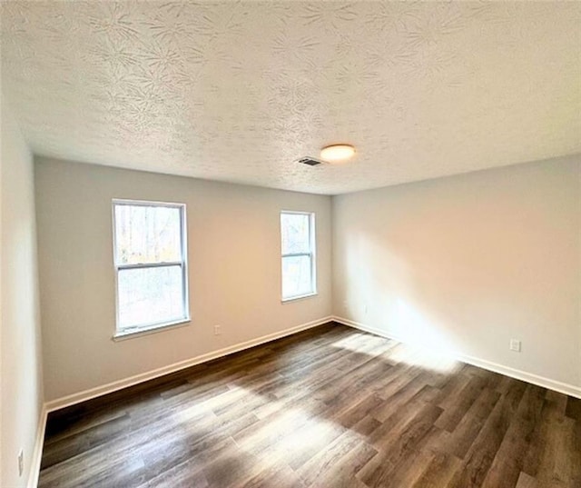 unfurnished room featuring dark wood-type flooring and a textured ceiling