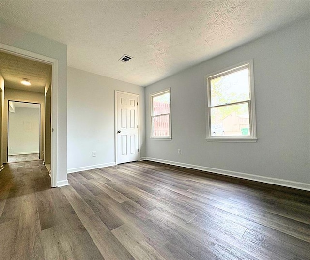 unfurnished bedroom with dark hardwood / wood-style floors and a textured ceiling