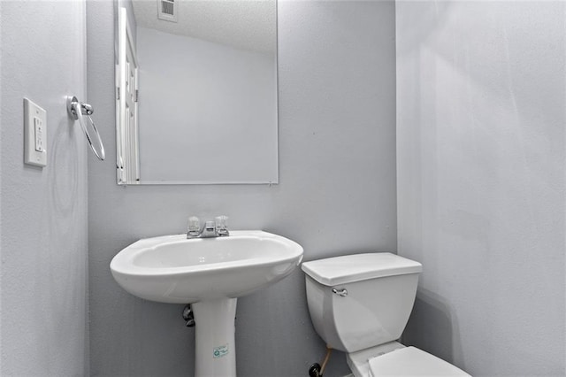 bathroom with a textured ceiling and toilet