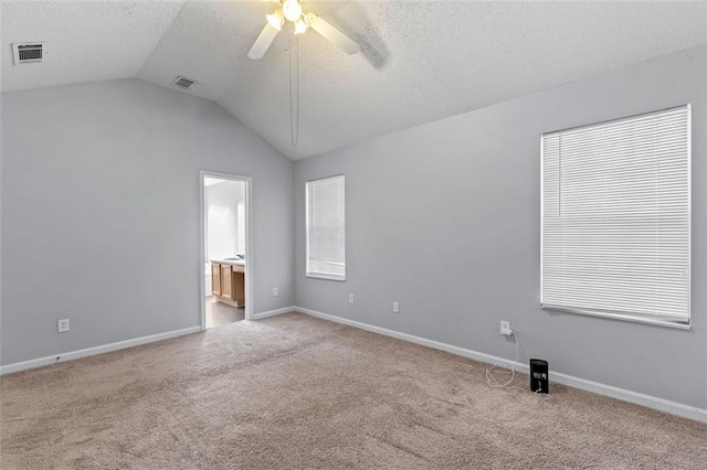 unfurnished room with a textured ceiling, ceiling fan, light colored carpet, and lofted ceiling