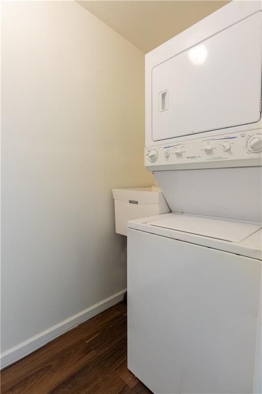 5150 Rockford Ln, Stockbridge, GA 30281 - washroom featuring dark wood-type flooring, baseboards, stacked washing maching and dryer, and laundry area