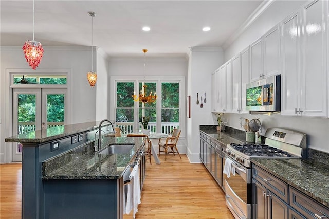 453 Carter Ave SE, Atlanta, GA 30317 - kitchen featuring stainless steel appliances, light wood-type flooring, a kitchen island with sink, dark stone countertops, and crown molding