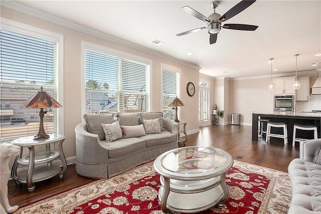 living room featuring baseboards, visible vents, dark wood finished floors, a ceiling fan, and ornamental molding