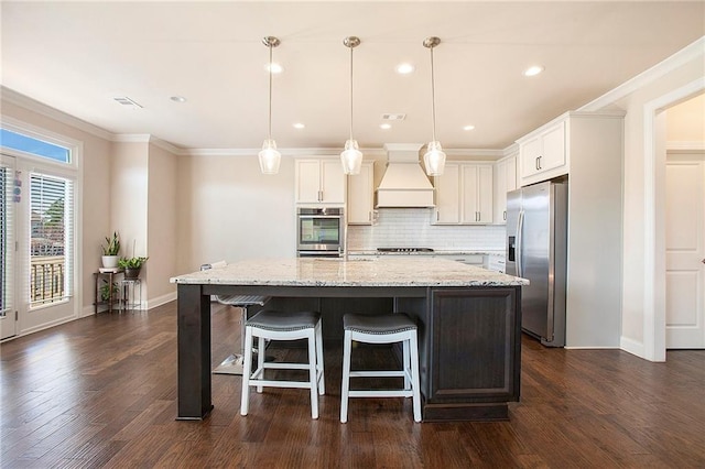 kitchen with visible vents, decorative backsplash, ornamental molding, stainless steel appliances, and premium range hood