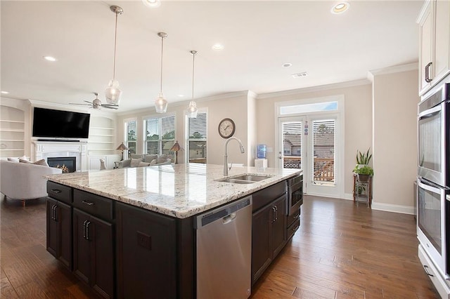 kitchen with appliances with stainless steel finishes, crown molding, a sink, and a lit fireplace