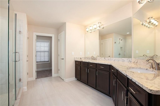 full bathroom featuring double vanity, a shower stall, baseboards, and a sink