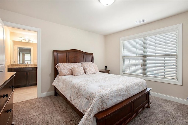 bedroom featuring light colored carpet, visible vents, connected bathroom, a sink, and baseboards