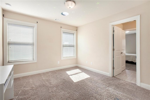 spare room with light carpet, baseboards, and visible vents