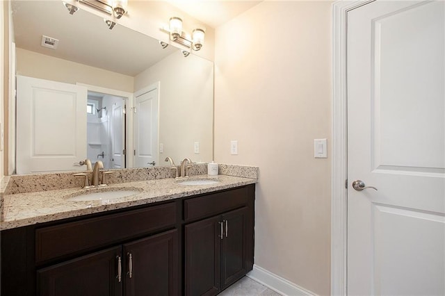 bathroom featuring double vanity, a sink, visible vents, and baseboards