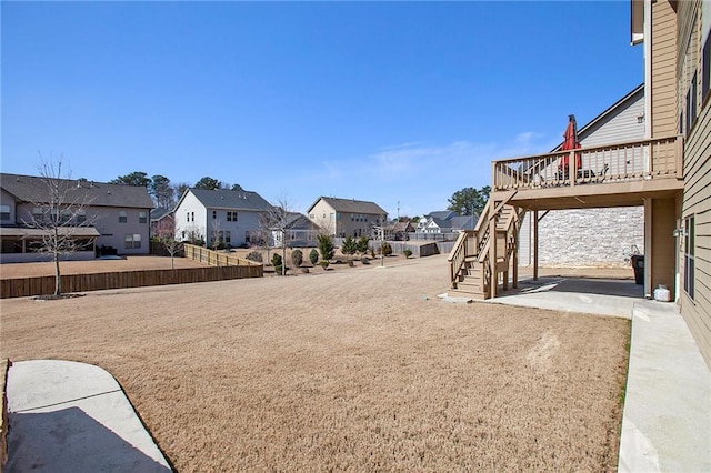 view of yard featuring fence, stairway, a wooden deck, a residential view, and a patio area