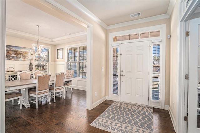 entryway featuring visible vents, a healthy amount of sunlight, ornamental molding, dark wood-style floors, and an inviting chandelier