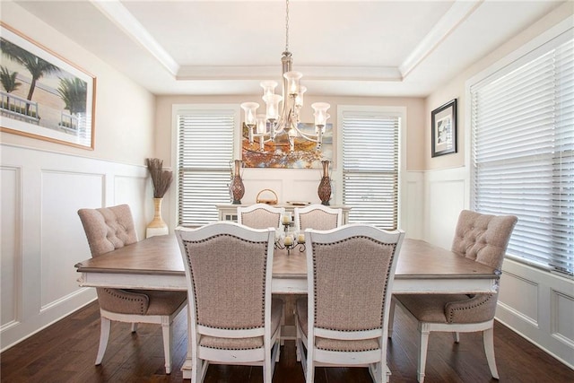 dining room with a tray ceiling, dark wood-type flooring, and a decorative wall