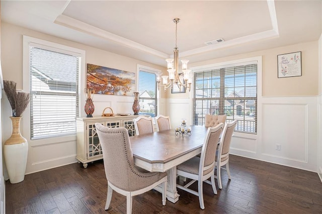 dining area featuring dark wood-style floors, a raised ceiling, visible vents, and a healthy amount of sunlight