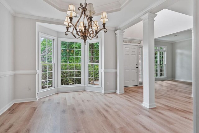 2934 Mill Grove Ter, Dacula, GA 30019 - unfurnished dining area with a chandelier, light wood-style floors, crown molding, a tray ceiling, and ornate columns