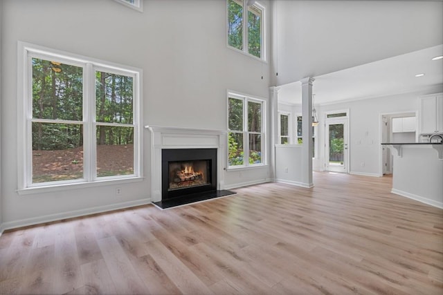 2934 Mill Grove Ter, Dacula, GA 30019 - unfurnished living room featuring a warm lit fireplace, a towering ceiling, and light wood-style floors