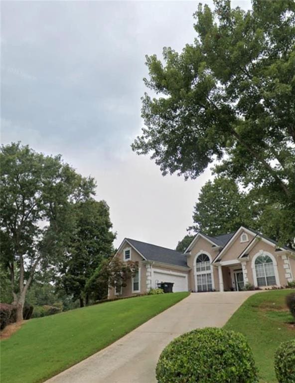 view of front of house with concrete driveway and a front lawn