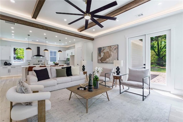 living area featuring light wood-style floors, ceiling fan, recessed lighting, and beamed ceiling