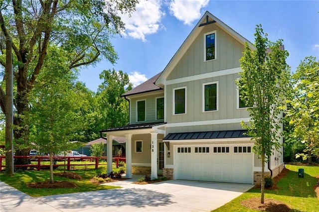 view of front facade featuring board and batten siding, an attached garage, driveway, a front yard, and a standing seam roof
