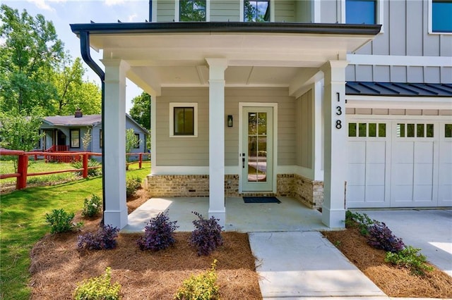 entrance to property with board and batten siding, fence, a porch, an attached garage, and concrete driveway