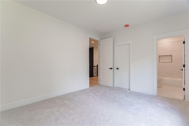 unfurnished bedroom featuring carpet flooring, baseboards, and ensuite bathroom