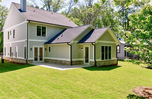 rear view of property featuring french doors, a lawn, board and batten siding, and a patio
