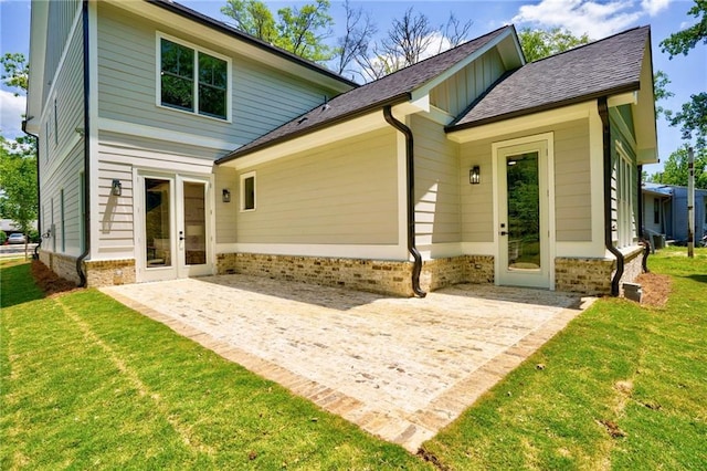 rear view of property featuring a lawn, a patio, and brick siding