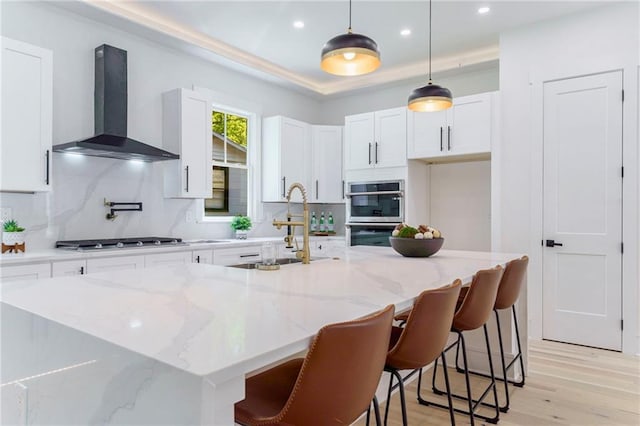kitchen with wall chimney exhaust hood, a sink, stainless steel appliances, backsplash, and recessed lighting