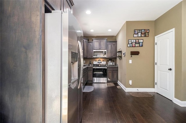 kitchen with appliances with stainless steel finishes, light countertops, baseboards, dark brown cabinetry, and dark wood-type flooring