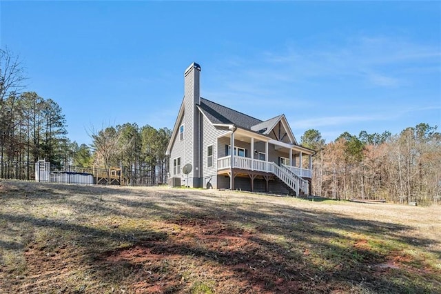 exterior space featuring fence, a porch, a chimney, and a front lawn