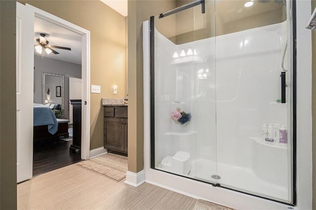 full bath with wood finished floors, ensuite bath, a stall shower, baseboards, and ceiling fan