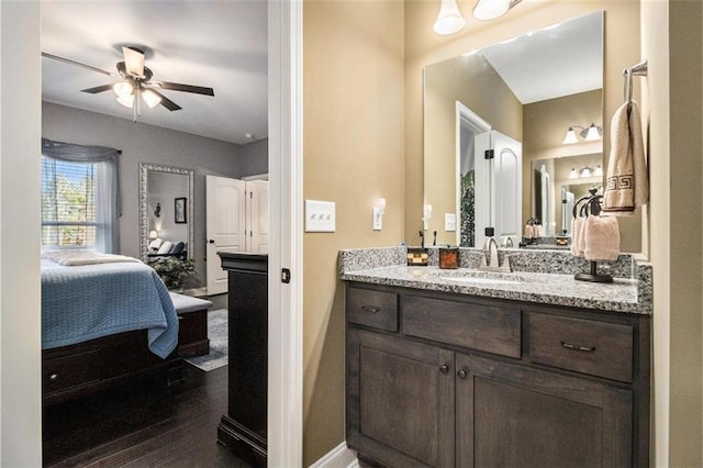 bathroom with vanity, connected bathroom, wood finished floors, baseboards, and ceiling fan