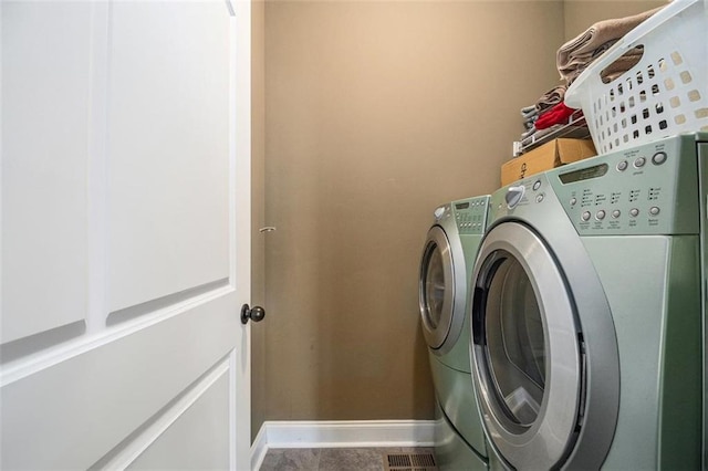 washroom with laundry area, baseboards, and washer and dryer