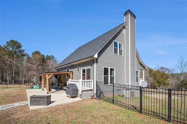 rear view of property with a patio, a chimney, fence private yard, and a yard