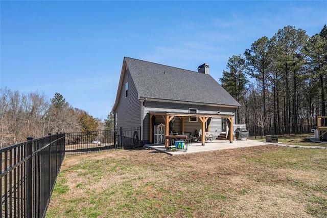 rear view of house with a lawn, a fenced backyard, a shingled roof, and a patio