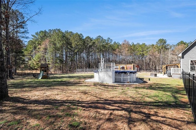 view of yard with fence, a covered pool, and a playground