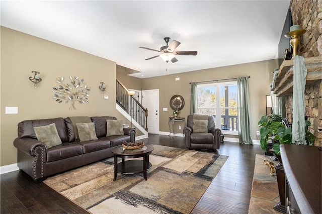 living room featuring baseboards, ceiling fan, stairs, and dark wood finished floors