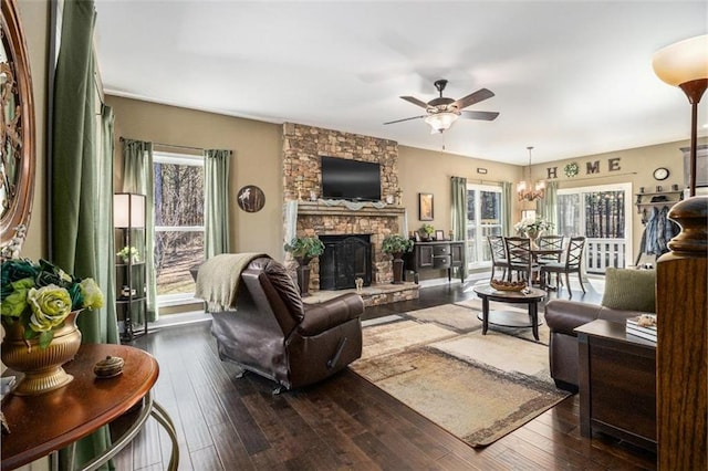 living room with a fireplace, a ceiling fan, and dark wood finished floors