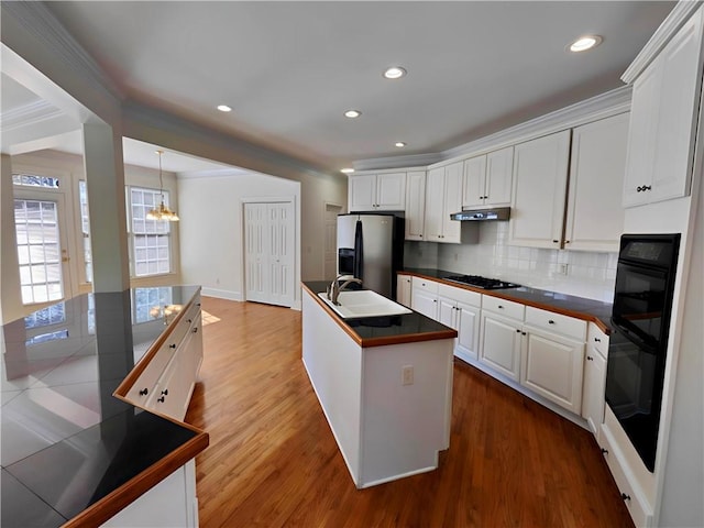 kitchen with black appliances, tasteful backsplash, a sink, and white cabinetry