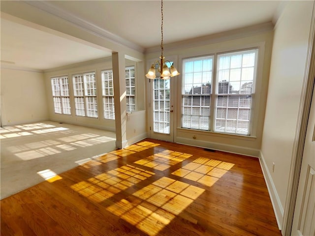 entryway with baseboards, ornamental molding, a notable chandelier, and wood finished floors