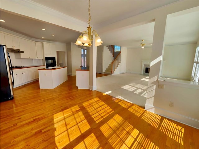 kitchen with light wood-style floors, freestanding refrigerator, white cabinetry, and a fireplace